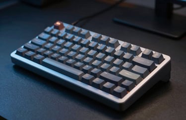 A close-up of a high-end mechanical keyboard on a dark desk in a North American / US office, lit with dramatic Steel Blue lighting.