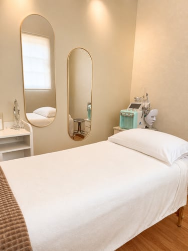 Cabina profesional para tratamientos faciales con camilla de masaje, espejos ovalados dorados y máqu