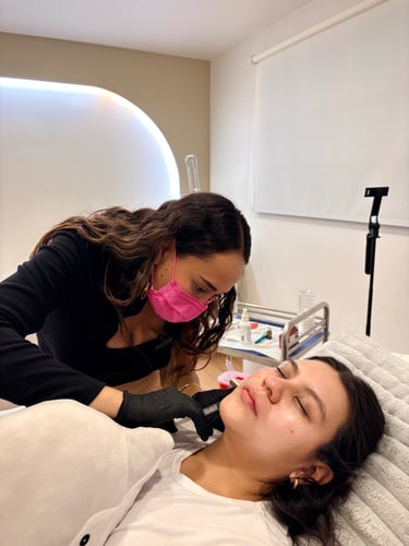 Professional esthetician performing a cosmetic facial procedure on a client in a clinical spa setting.
