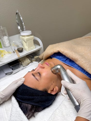 Esthetician performing a professional microdermabrasion facial treatment on a female client.