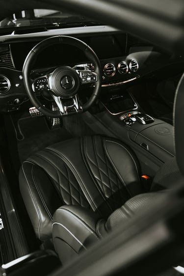 Luxury interior of a Mercedes-Benz AMG with black quilted leather seats and sport steering wheel.