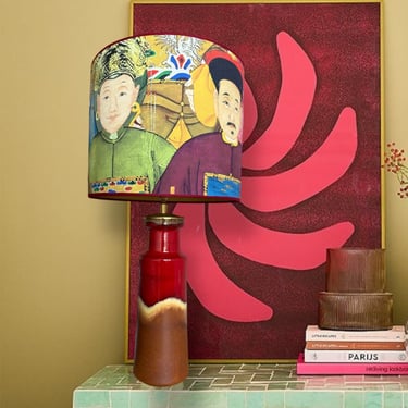 Vintage ceramic table lamp with Chinoiserie portrait lampshade on a green tiled sideboard.