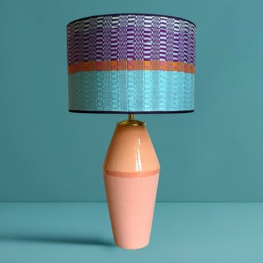 Mid-century modern table lamp with a pink ceramic base and a colorful patterned drum lampshade.