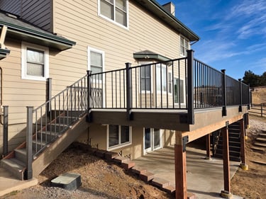 Finished elevated deck with black metal railing and integrated stairs by Elk Valley Contractors.