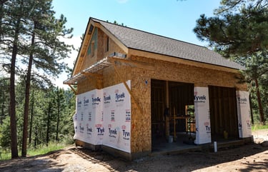 Exterior garage framing with weather-protective house wrap.