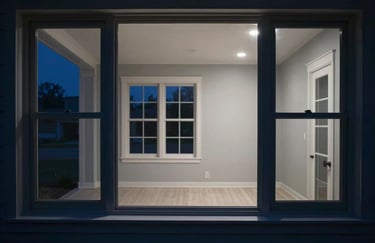 Photography of a brightly lit North American / US home interior at night, seen through a window, signifying safety and power, deep slate blue and pale mist grey lighting.