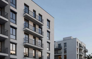A minimalist exterior facade of a luxury apartment complex in Vilnius, modern materials, evening blue sky background, soft architectural lighting.