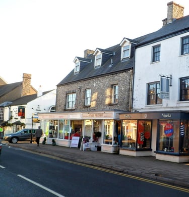 Traditional stone storefronts and boutiques along a historic British high street at sunset.