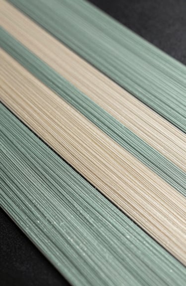 An elegant composition of traditional Japanese silk threads in muted sage, soft celadon, and warm cream colors.