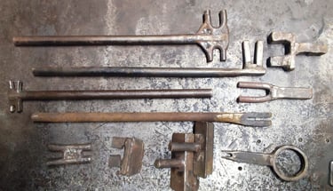 Tradiciniai kalviški įrankiai - šakutės, įvairaus storio metalo lankstymui, išdėlioti kalvystės dirbtuvėse