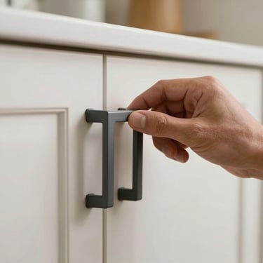 Macro photography of a worker's hand installing a sleek, dark gray handle on a brand new kitchen cabinet in a Los Angeles home.