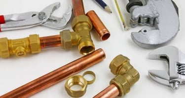 Selection of professional plumbing tools, copper pipes, and brass fittings 