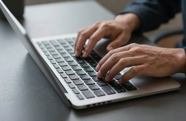 Professional hands typing on a modern slim keyboard on a dark slate grey desk surface.