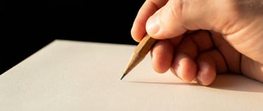 Main qui tient un crayon de papier au-dessus d'une feuille blanche