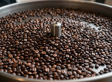 Action shot of freshly roasted coffee beans cooling in a large rotating circular tray, creating a sense of movement and scale.