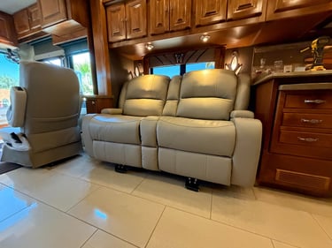 Luxurious beige leather theater seating recliner inside a modern motorhome with wood cabinets.