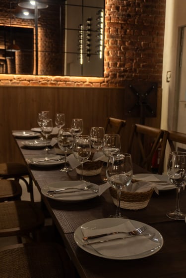 Elegante mesa lista para compartir, con copas de vino y platos cuidadosamente presentados.