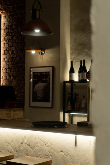 Interior de vinoteca de estilo rústico, con cálidas lámparas colgantes y paredes de ladrillo visto.