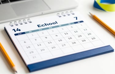 A close-up of a school event calendar on a clean desk next to a pencil and a colorful ribbon. The mood is organized and proactive, highlighting the brand colors in the paper and accessories.