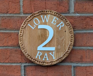 Bespoke hand-finished circular oak house sign with deep-carved 3D numerals and decorative border