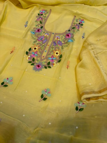 Yellow unstitched dress material with intricate floral embroidery on the neckline.