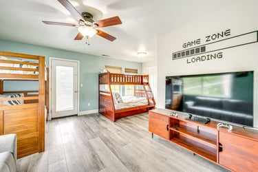 Modern kids bedroom and game room featuring wooden bunk beds and a large flat screen TV.
