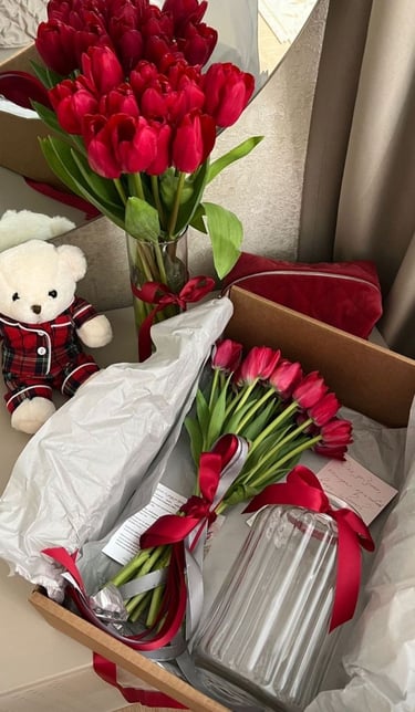 ramo de tulipanes color rojo en un florero con un osos de peluche color blanco