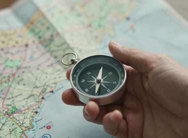 A detail shot of a hand holding a compass over a map, representing stewardship, direction, and moral leadership. Tones of #3D5B5F and #F8F4F0.