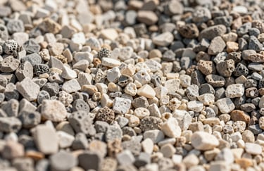 A macro photograph of high-quality aggregate stone and gravel samples, showing different grades of sub-base and rockery stone used in UAE infrastructure projects, with clean lighting and neutral beige tones.