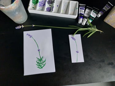 Acrylic painting of lavender flowers on paper with art supplies and fresh lavender sprigs.