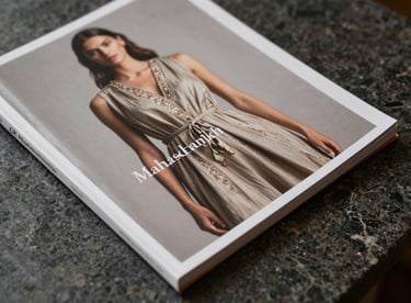 Close-up of a high-end fashion catalog for Mahashankh Fashion resting on a polished dark stone surface.