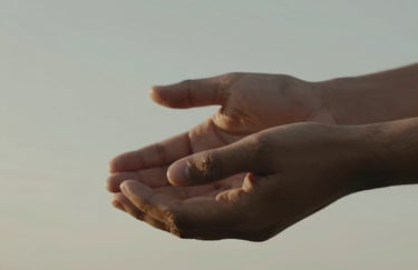 A close-up shot of two hands held in a supportive gesture, captured in a warm, Soft Sky Grey light, representing human connection and anthropology.