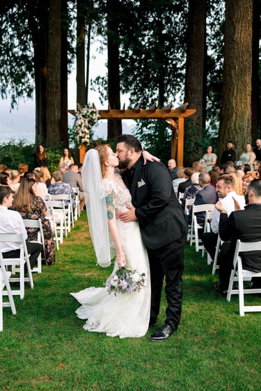 Vancouver bride and groom sharing a first kiss at an outdoor forest wedding ceremony