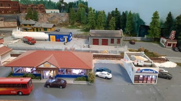 Beena gas depot with some fast food outlets in the foreground and the station behind the depot.