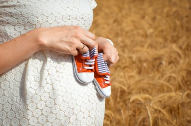 Femme enceinte qui tient des petites chaussures sur son ventre, gender reveal