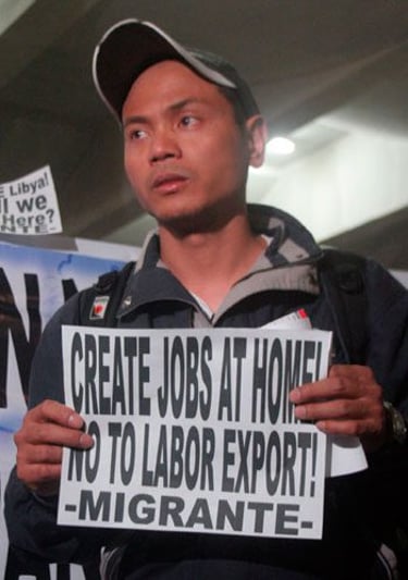A Migrante activist holding a protest sign advocating for local jobs and an end to labor export.