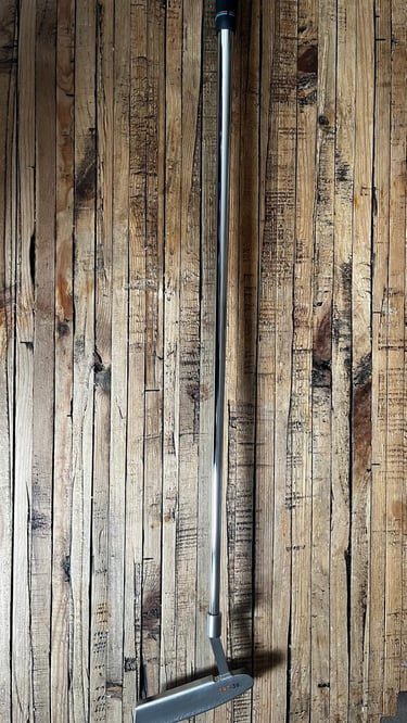 Brace forged golf putter on wooden surface