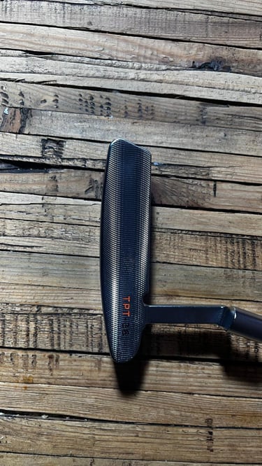 Brace forged golf putter on wooden surface