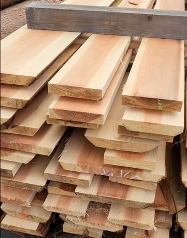 Stacked raw cedar lumber planks at a sawmill for woodworking and construction projects.