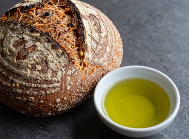 Artisanal bread next to a small bowl of vibrant green olive oil, highlighting the gourmet quality.