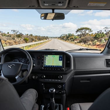 A driver's perspective from inside a clean, modern truck cabin, showing a professional GPS interface and a clear South American highway ahead.