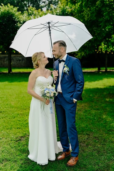 Brautpaar unter einem Regenschirm bei einem Hochzeitsshooting im Park von Schloss & Gut Liebenberg