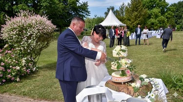 Glückliches Brautpaar beim Anschneiden der Hochzeitstorte im Freien, authentische Hochzeitsfotografie in Oranienburg.