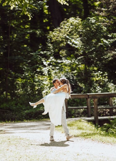 Bräutigam trägt die Braut im Wald, natürliche Hochzeitsreportage im Grünen