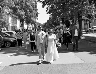 Auszug des Brautpaares nach der Trauung in Rheinsberg, begleitet von Hochzeitsgästen auf der Straße.