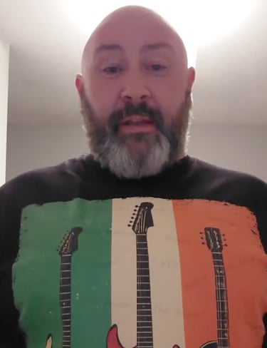 The Irish musician, Cathal Daly wearing a graphic t-shirt featuring three electric guitars.