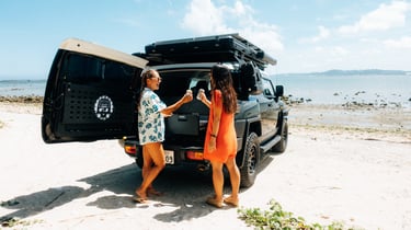 Two women enjoying drinks by their Toyota FJ Cruiser parked on the beach in Okinawa. | Evertrail Okinawa