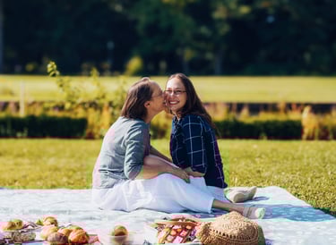 Mutter und Tochter lachen gemeinsam bei einem Picknick im Park – natürliches Familienportrait im Freien