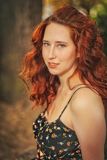 Nahaufnahme einer jungen Frau mit roten Locken und grünen Augen im schwarzen Blumenkleid – emotionales Portrait von LensandLo
