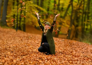 Frau wirft Herbstblätter in die Luft und lacht, aufgenommen von Lens & Look im Wald bei Oranienburg | Cinematische Portraitfo